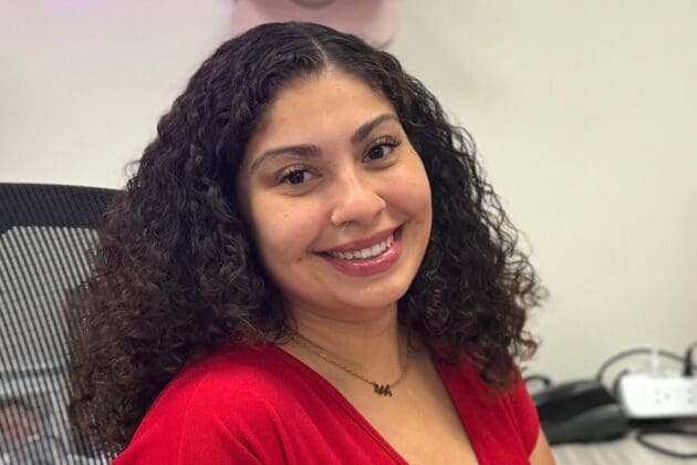 photo of program assistant Gabby sitting in office and smiling